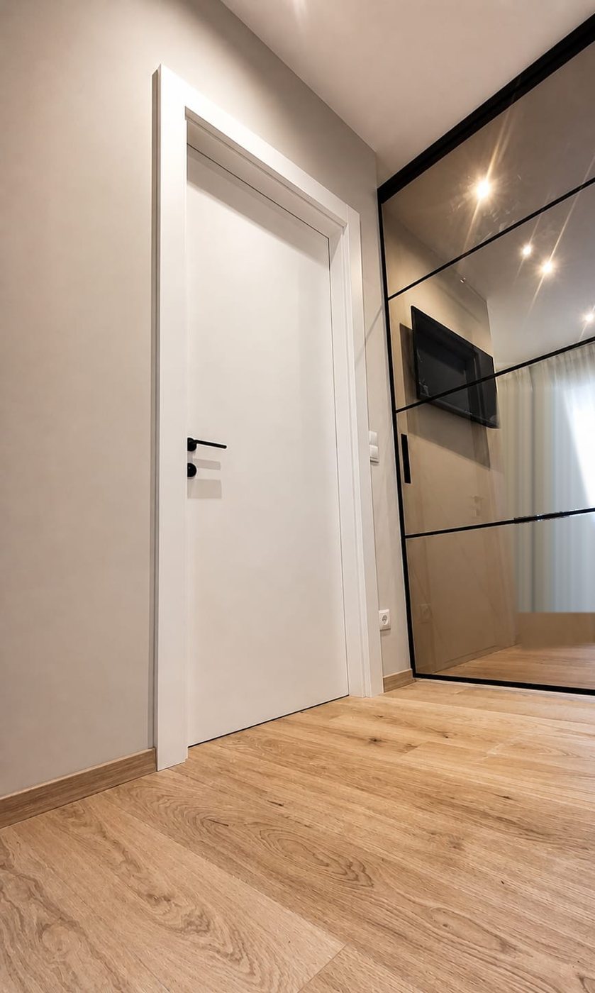 Porta bianca con maniglia nera accanto a una parete vetrata nera