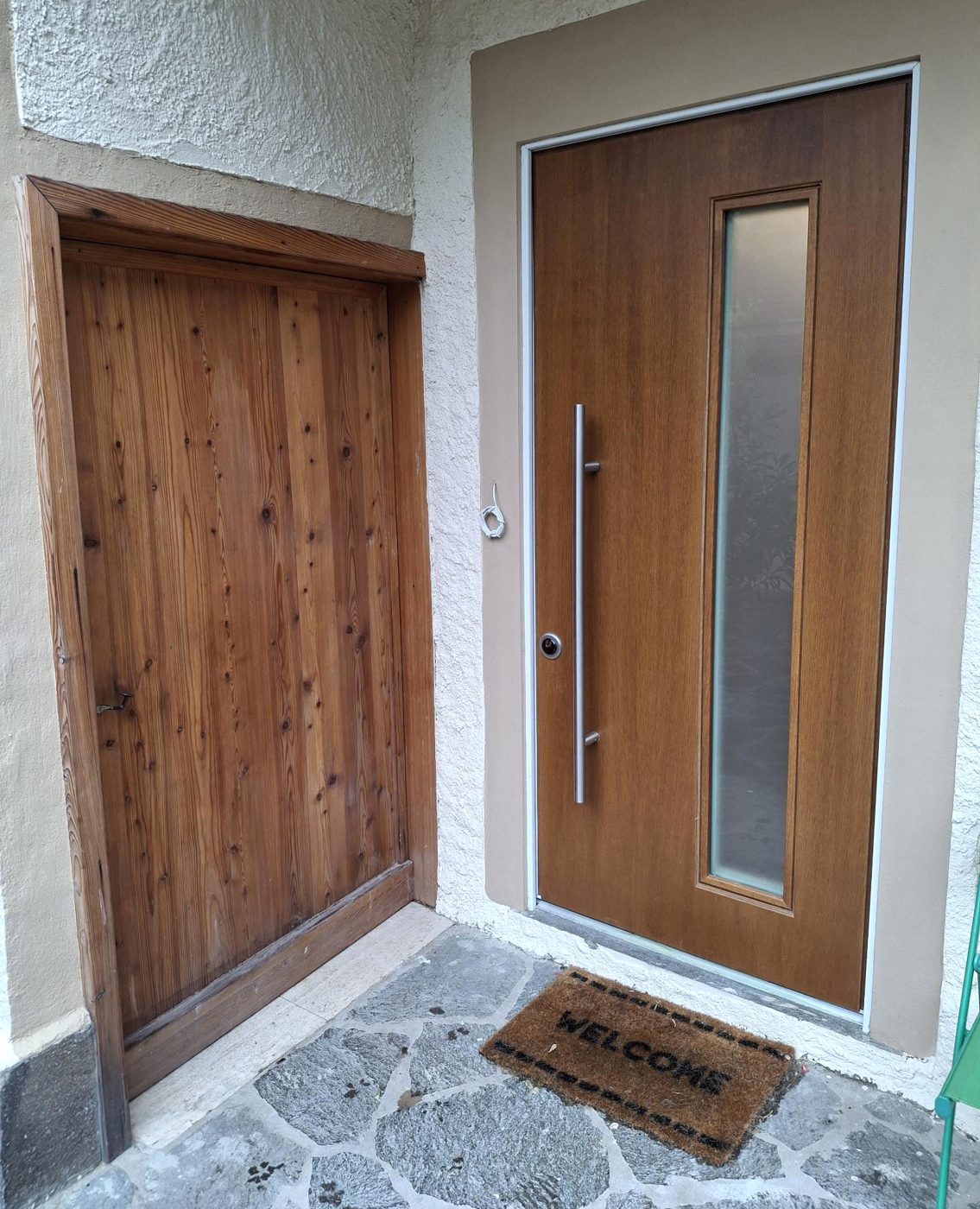 Portoncino d'ingresso effetto legno con vetro accanto a una porta in legno